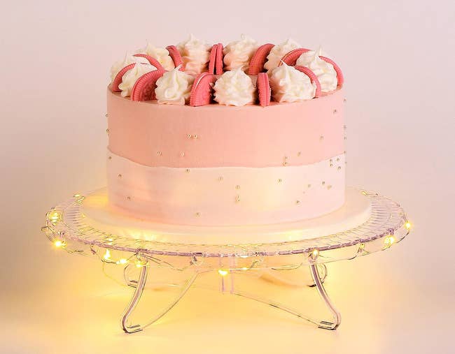 cake stand with string lights lit up underneath holding a cake