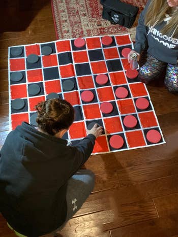 Two people playing a large floor checkerboard game