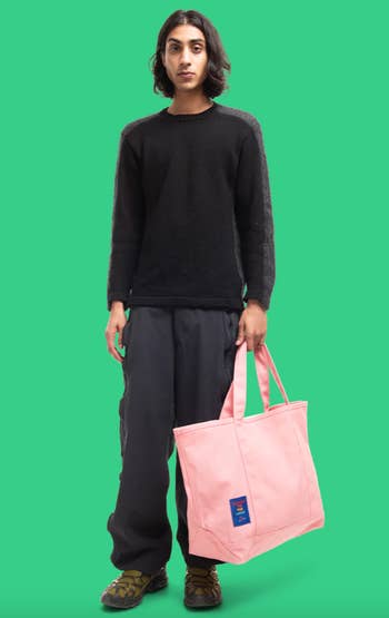 Model holding the pink canvas mega-tote against a green background