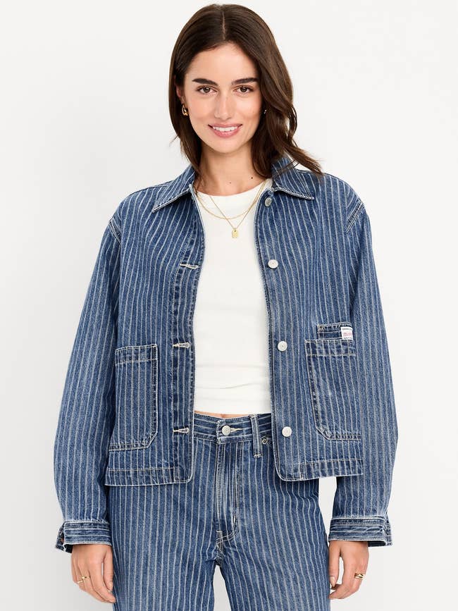 Woman successful denim overgarment and jeans with vertical stripes, wearing a achromatic top