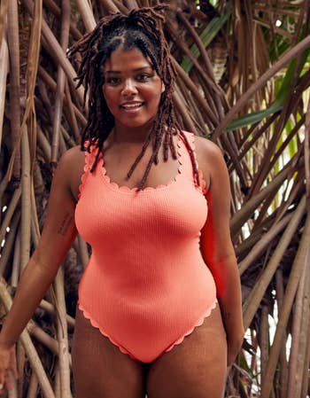 a model wearing the one piece in coral pink