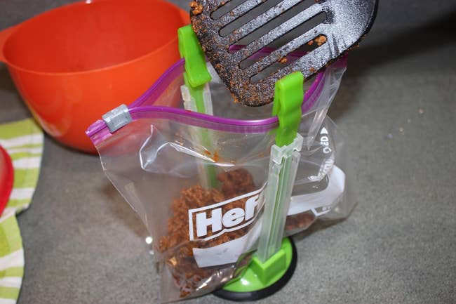 the bag rack holding a freezer bag with a spatula scooping in meat