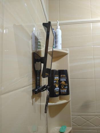 Corner shower shelf with various toiletry products and a hair straightener