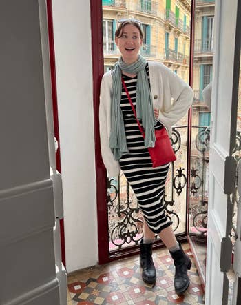 Entertainment news Celebrity gossip Movie and TV show updates Latest celebrity news Trending entertainment stories A person stands stylishly in a striped dress, cardigan, and scarf, carrying a red bag, in an elegant interior space