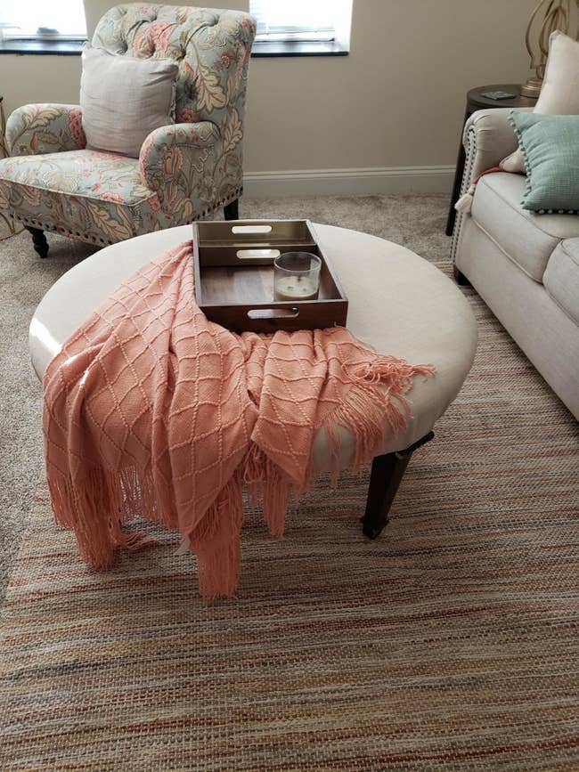reviewers peach-colored throw draped over an ottoman