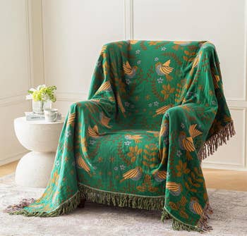 Armchair draped with a patterned propulsion  featuring vertebrate  and floral designs, adjacent  to a tiny  circular  array  with a works  and teacup