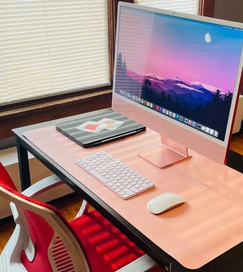 Reviewer photo of the pink desk pad under iMac, mouse, and keyboard
