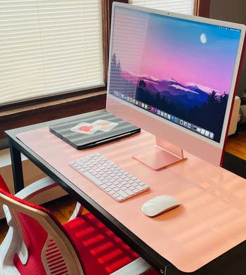 Reviewer photo of the pink desk pad under iMac, mouse, and keyboard