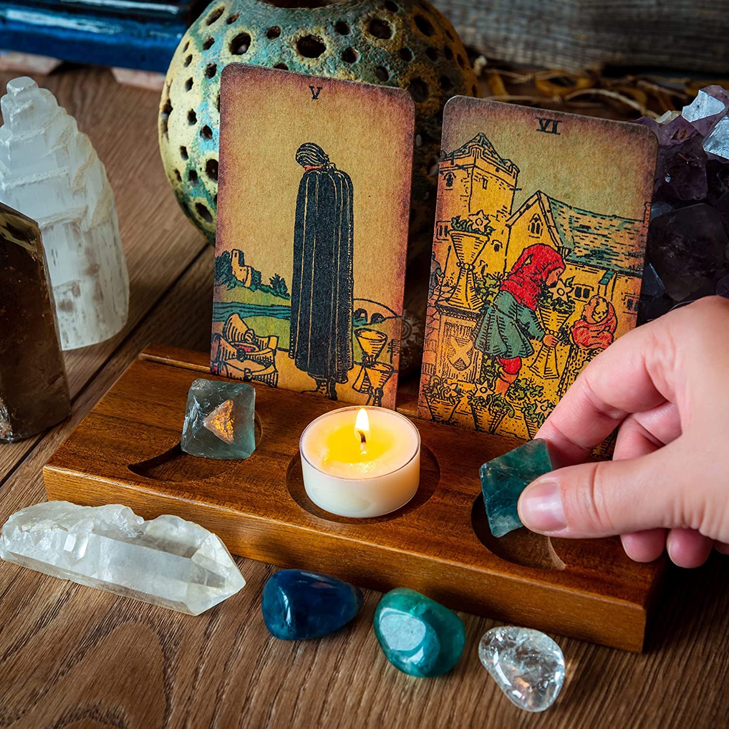 two tarot cards upright in wooden stand with space for a tea candle and stones
