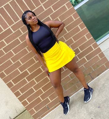 a reviewer wearing the skirt in yellow paired with a black tank top