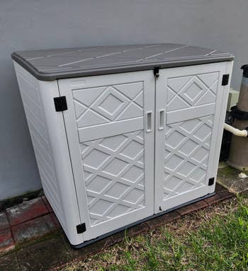Outdoor storage box with a diamond pattern and double doors, suitable for garden tool organization