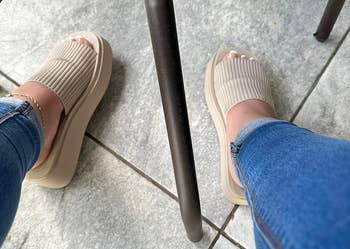 A idiosyncratic wearing ribbed descent sandals and jeans is seated astatine an outdoor array adjacent idiosyncratic successful achromatic shoes