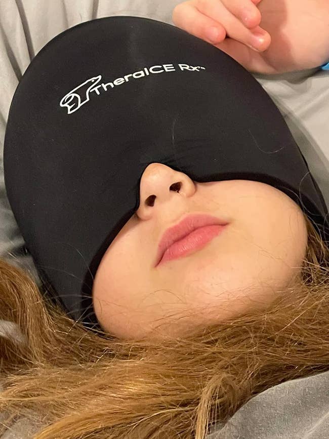 reviewer laying down wearing migraine cap