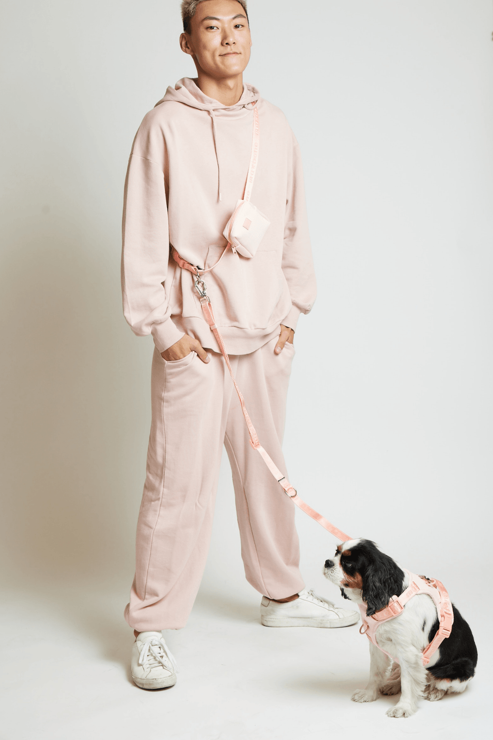 a model wearing the treat pack connected to the leash and dog harness in peach