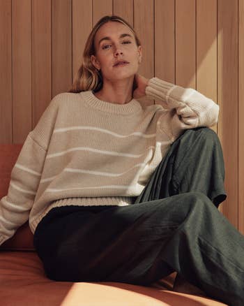 Person seated casually, wearing a relaxed-fit sweater and wide-leg pants, acceptable   against a woody  backdrop, successful  a cozy, shopping-themed article
