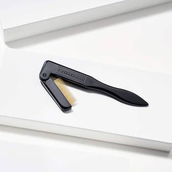 Eyebrow grooming instrumentality with foldable metallic teeth for precise shaping, laid connected achromatic surface