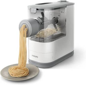 the white pasta maker extruding fresh spaghetti