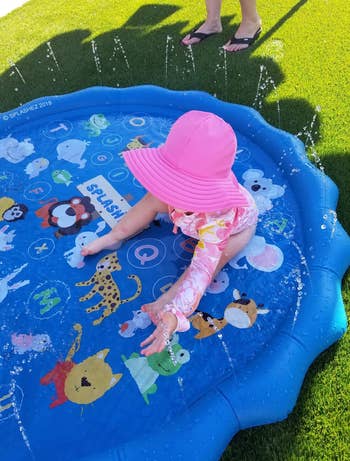 a reviewer's baby sitting in the splash pad 