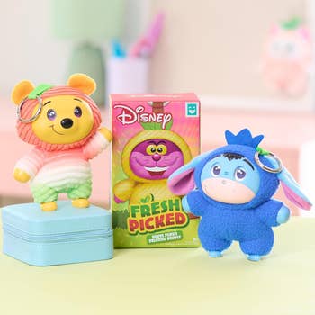 Two Disney-themed keychain plushies, a bear and a donkey, are displayed next to packaging labeled