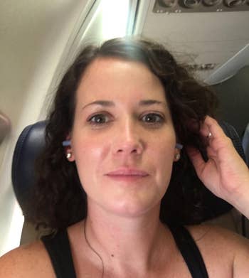 The reviewer with the earbuds sitting on an airplane