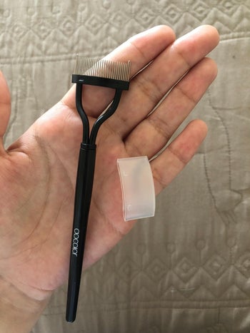 Reviewer holding their eyelash comb separator and the comb's protective cover 