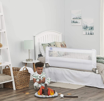 child playing in room with adjustable bed rail on toddler bed
