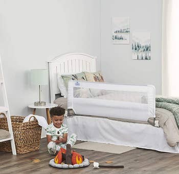 child playing in room with adjustable bed rail on toddler bed 