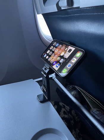 same reviewer's photo of the phone mount attached to their folded down tray table