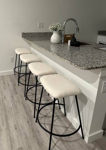 A modern kitchen island with three bar stools for home interior inspiration