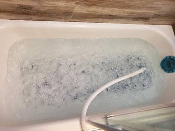 Bathtub with a h2o  pitchy  strategy   running, creating bubbles. The inheritance  features a wooden-textured wall