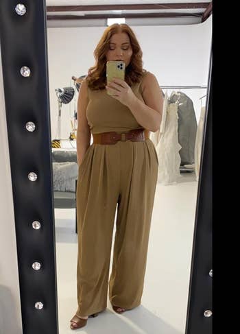 Reviewer in beige version of the jumpsuit, with a belt around it 