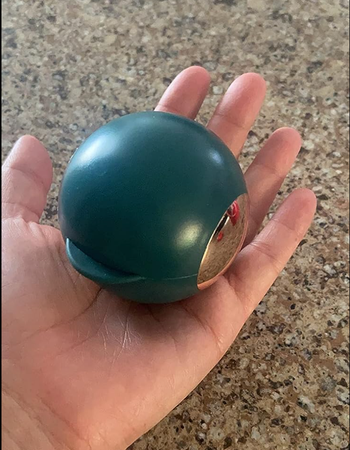 reviewer holding small green ball in their hand 