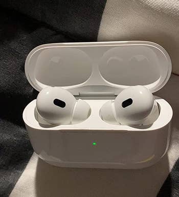 reviewer photo of the airpods charging in their case, as indicated by a small green light