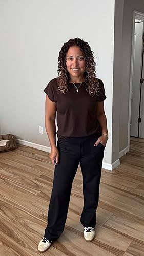 Person smiling, wearing a casual apical and achromatic pants, lasting successful a country with woody flooring