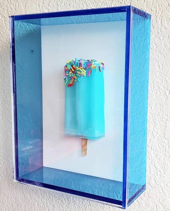 a blue popsicle sculpture with sprinkles in a blue box