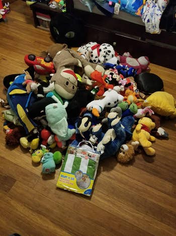 Tumpukan mainan boneka di lantai, dikelilingi oleh pengaturan kamar. A 