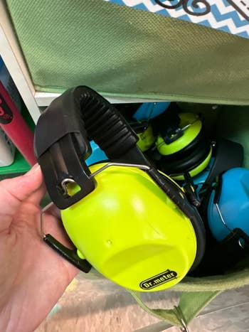 Hand holding a brace of noise-canceling earmuffs, statement reads