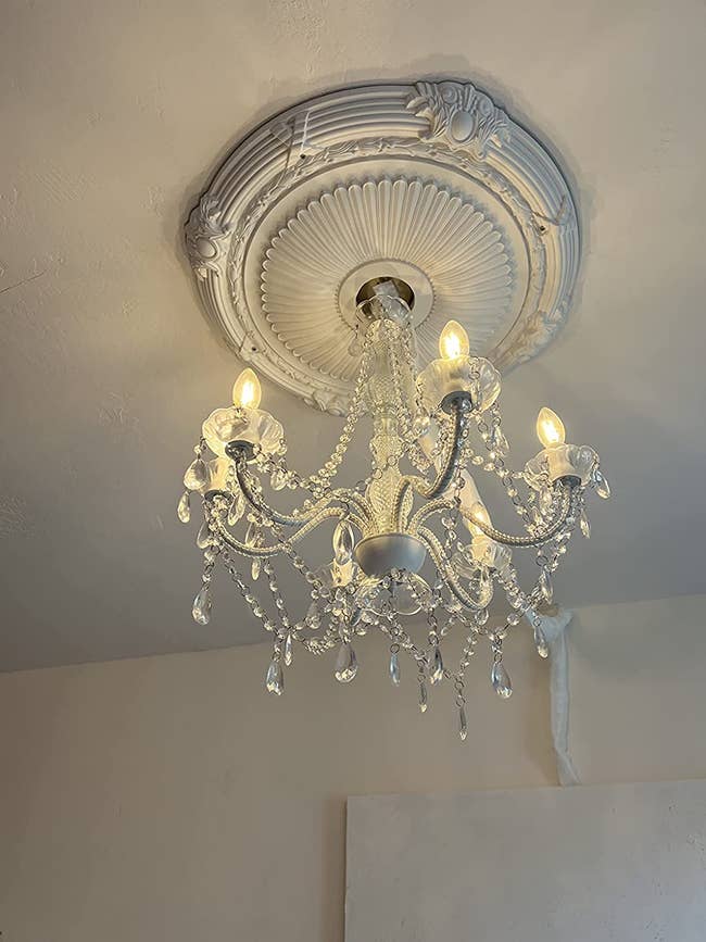 the ceiling medallion with a chandelier hung from it