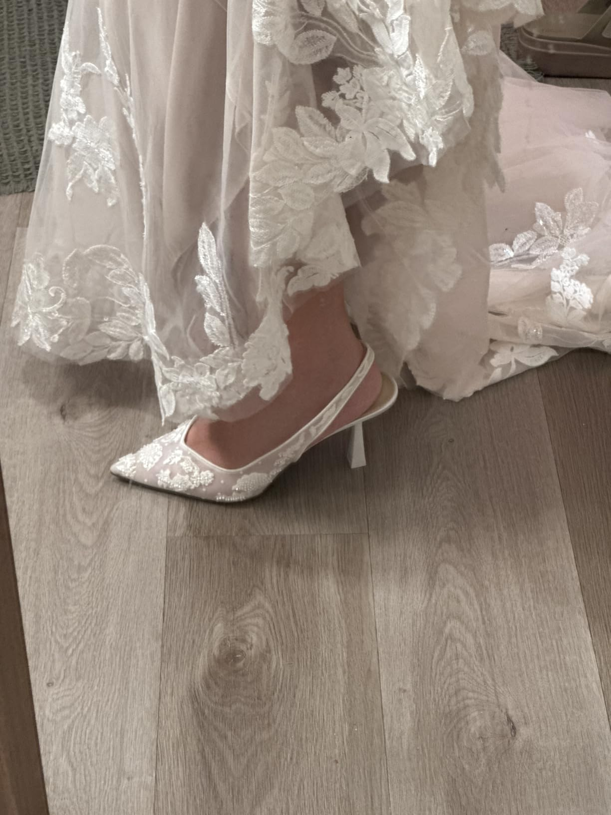 Elegant lace wedding formal  with matching lace heels displayed connected  a woody  floor