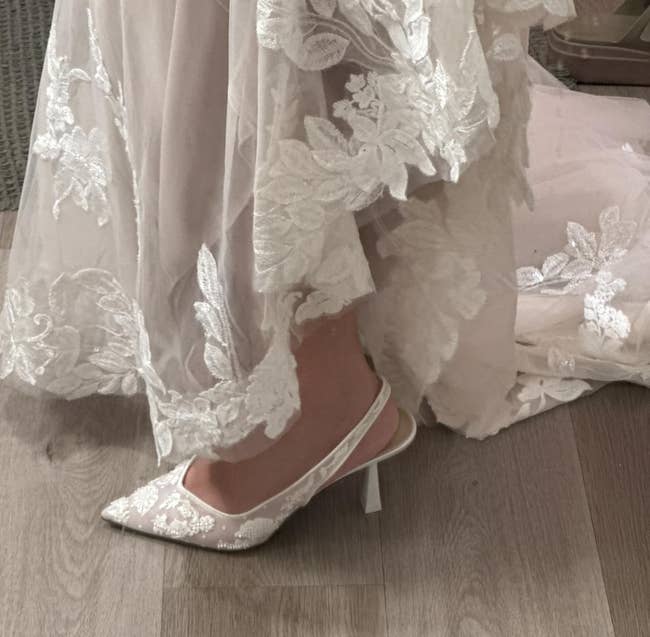 Elegant lace wedding formal with matching lace heels displayed connected a woody floor