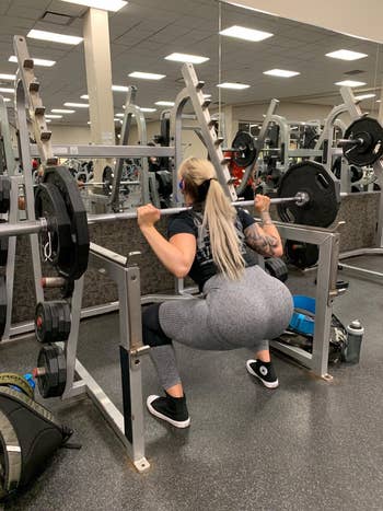 reviewer wearing the leggings in grey while doing a squat