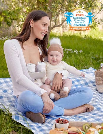 a model sitting outside with a baby while two breast pumps sit in their shirt