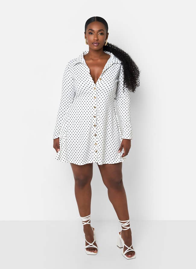 model in short white mini dress with black polka dots and long sleeves