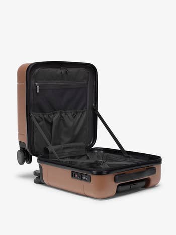 Open brownish hard-shell suitcase with interior pockets and adjustable straps