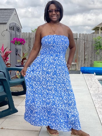 reviewer wears blue and white sleeveless floral sundress with brown sandals