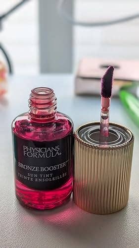 Physicians Formula Bronze Booster Sun Tint bottle with applicator on a table, highlighting a beauty product for a shopping article