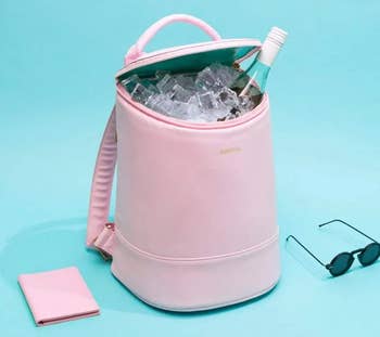 the pink cooler backpack filled with ice and holding a wine bottle 