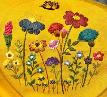 Embroidery of assorted flowers with a butterfly connected top, displayed connected a agleam background. Perfect for adding a charming interaction to location decor items