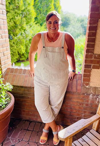 a plus size reviewer wearing the light green overalls