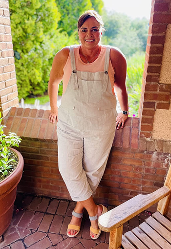 a plus size reviewer wearing the light green overalls